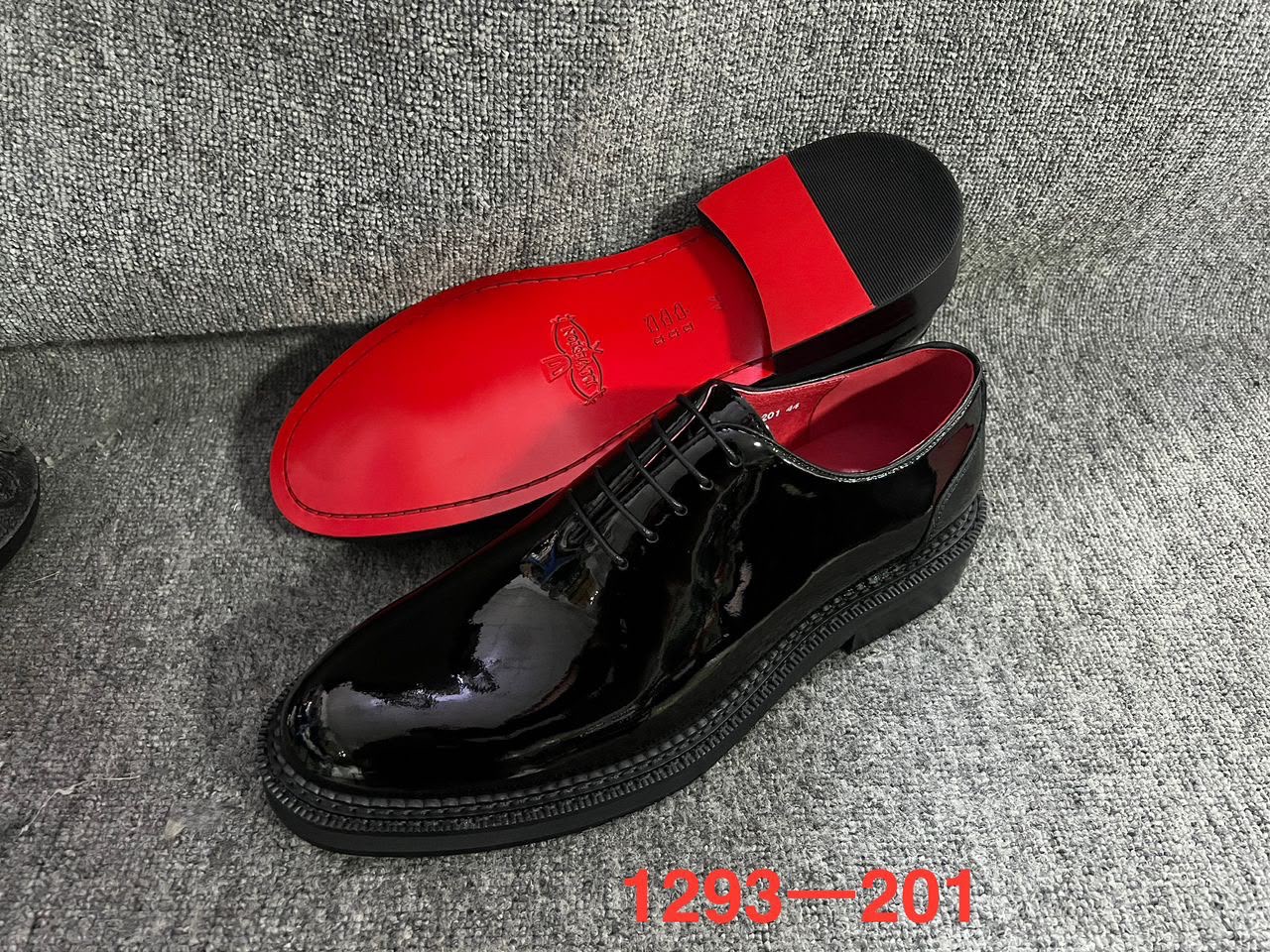 Black patent leather dress shoes featuring a shiny gloss finish and a classic lace-up oxford design.

Distinctive vibrant red soles paired with a black block heel and textured welt detailing along the base.