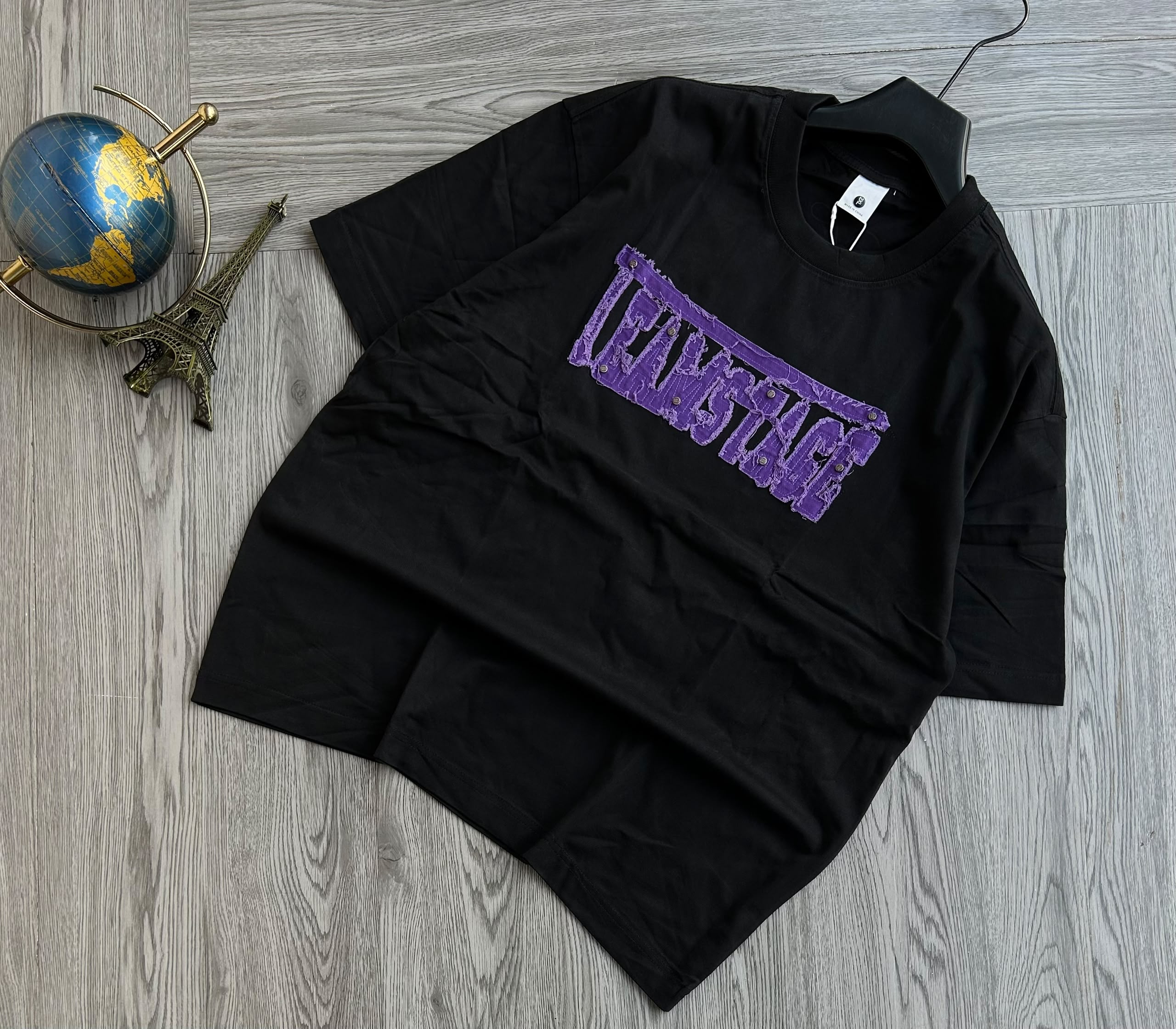 Features a vibrant, multi-color paint-splatter compass rose graphic printed on the left chest. Crafted from a thick cotton fabric, making it a casual streetwear piece.