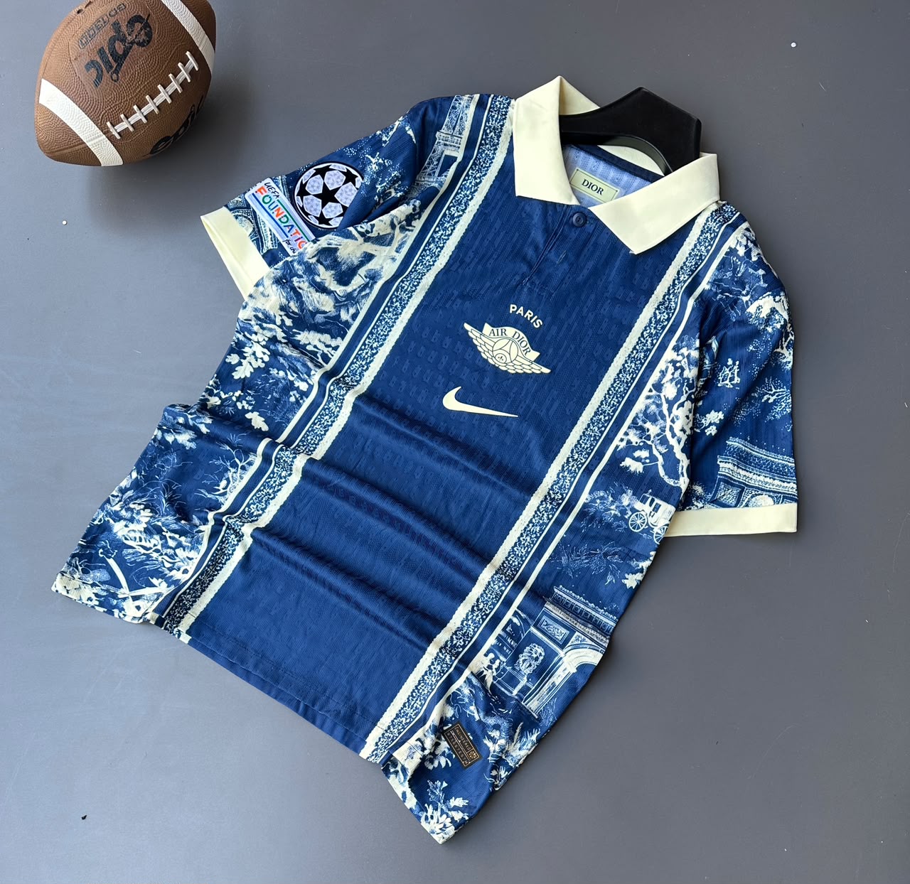 Features the iconic Trefoil logo, woven chest crest, front sponsor print, and official sleeve tournament badges